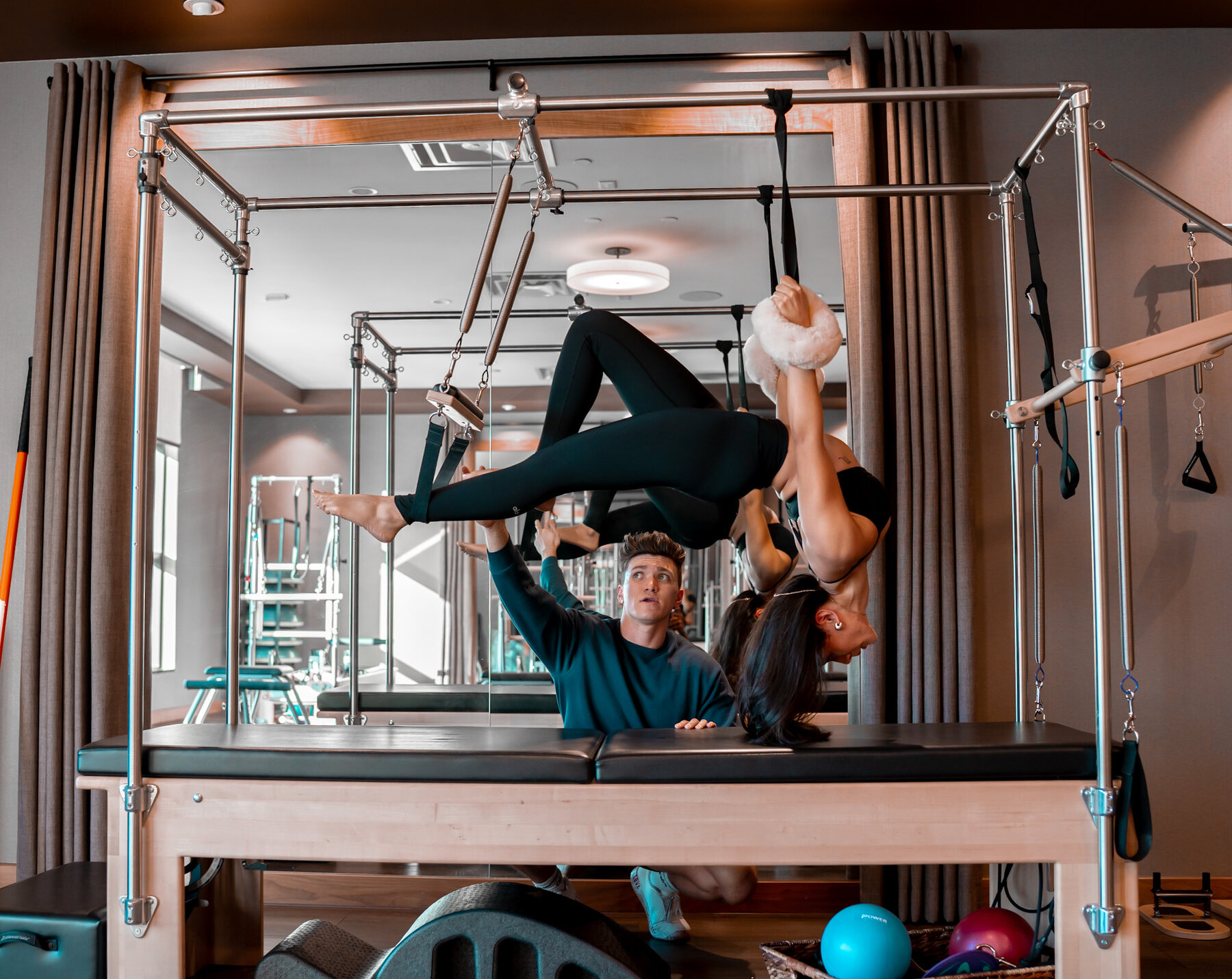 A guided Pilates session inside the studio, with an instructor supporting a client on Pilates equipment.